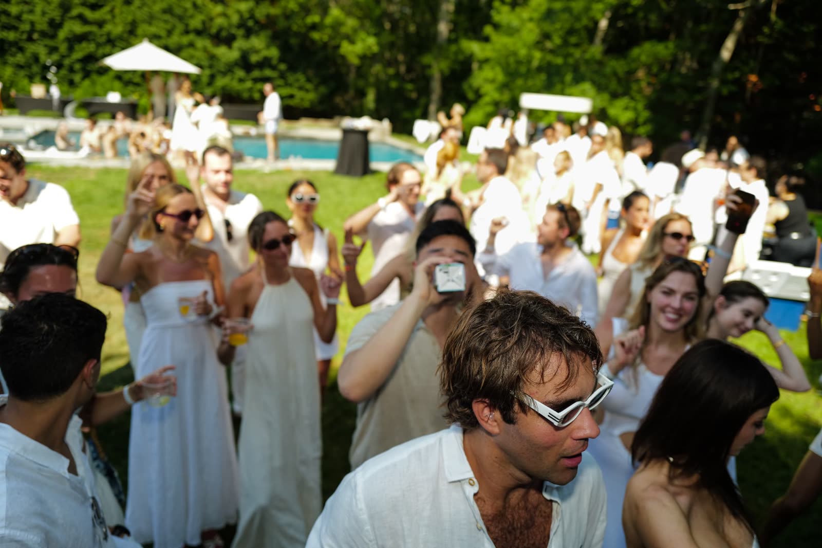 Crowd in all white across the lawn and pool