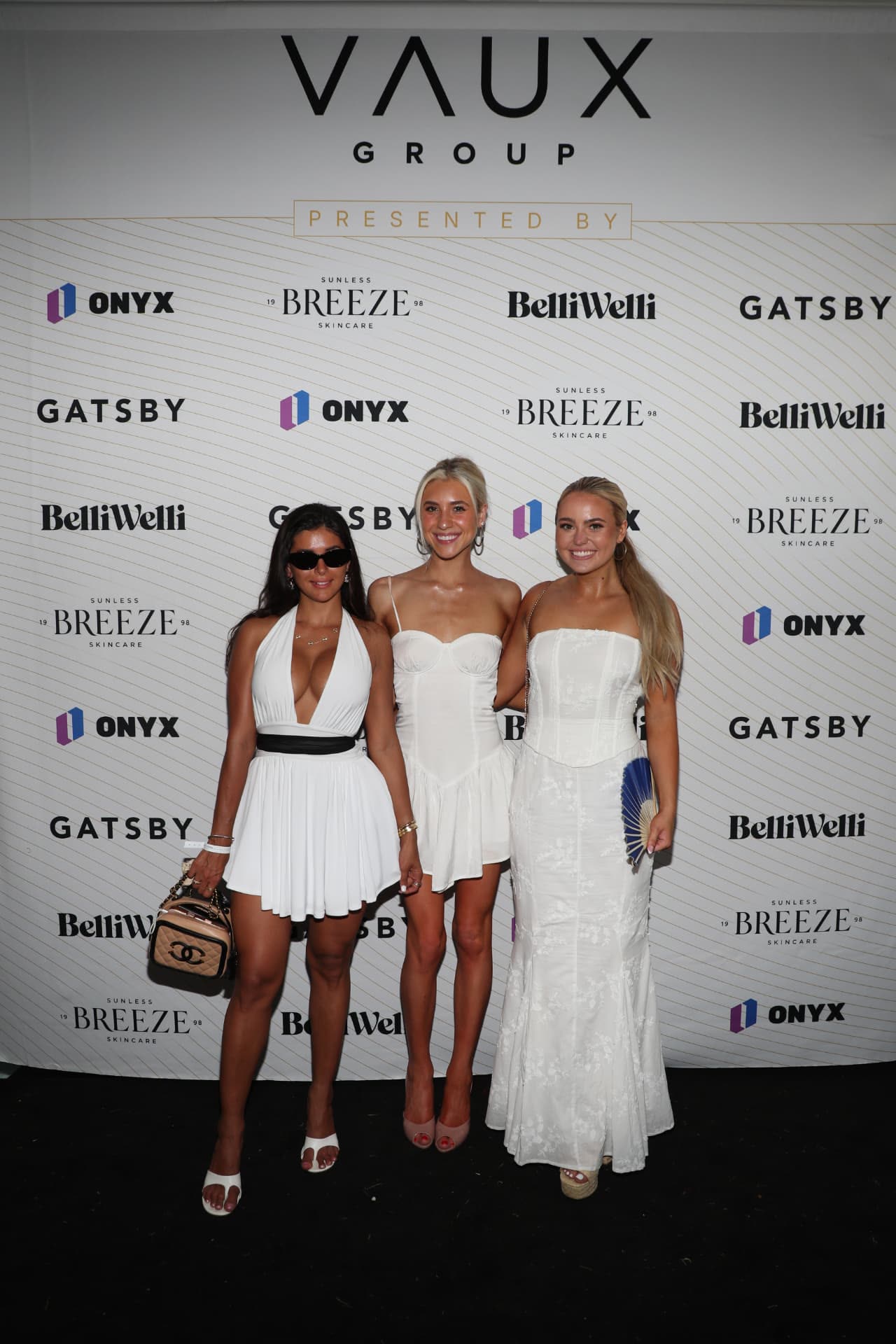 Guests in white on the VAUX Group step-and-repeat